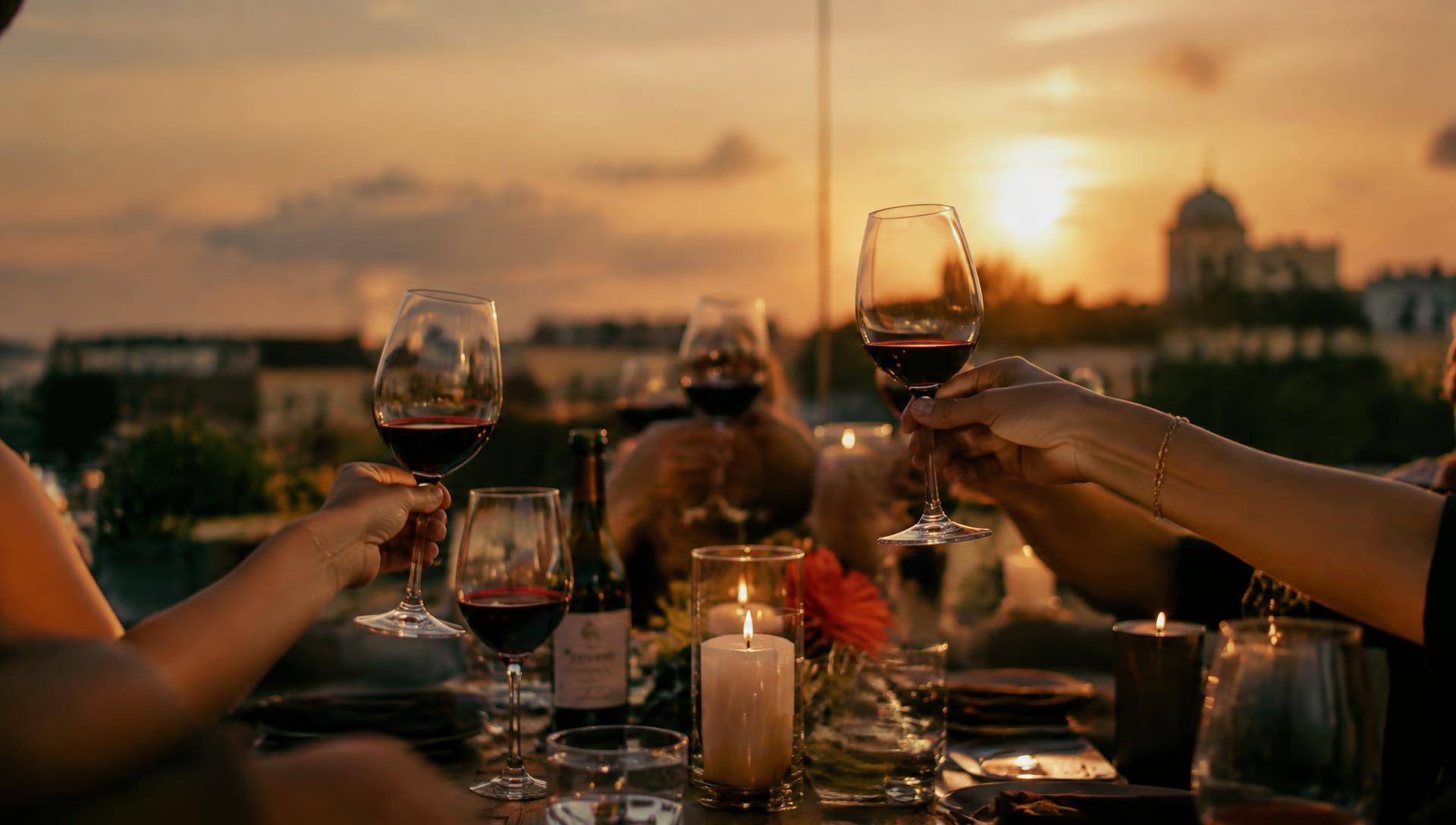 Guests raising glasses of wine at a rooftop table at sunset